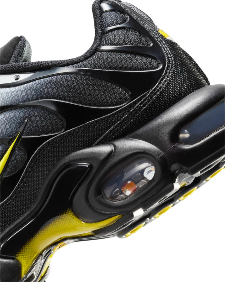 Close-up of black and yellow athletic sneakers with visible air cushioning unit.