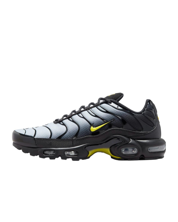 Black and grey Nike Air Max Plus sneakers with yellow swoosh accents