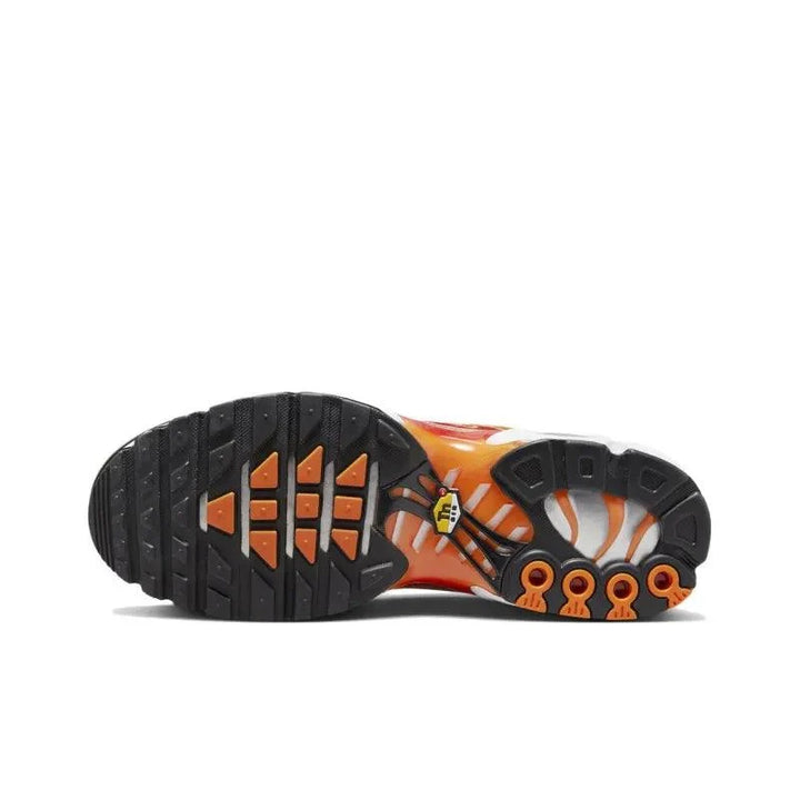 Sole view of orange and white athletic sneakers with black textured tread.
