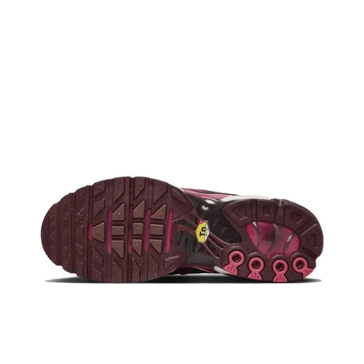 Sole view of burgundy and pink patterned athletic running shoes.