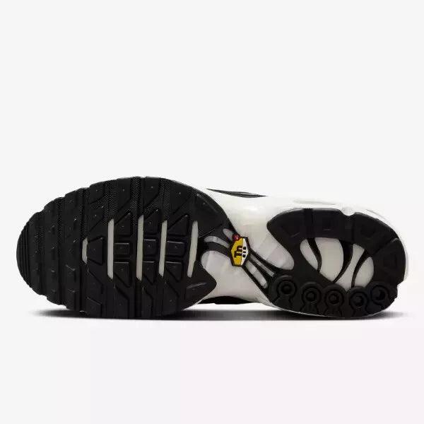 Sole view of a white and black athletic sneaker with a patterned rubber outsole.